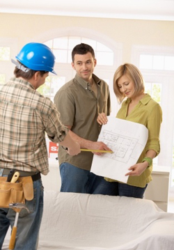 smiling couple discussing floor plan with home builder